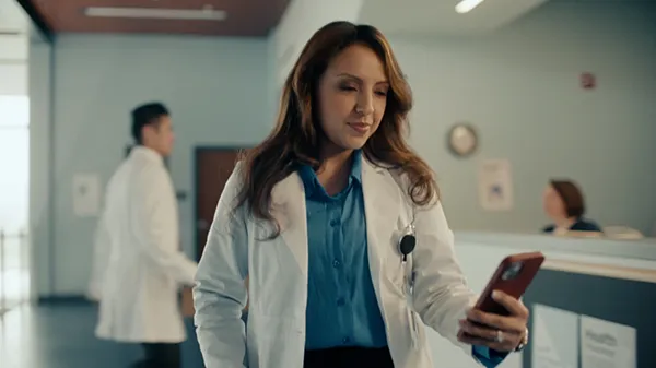Anna, as a doctor-in-residence, reviewing information on her phone as she walks down a medical office hallway